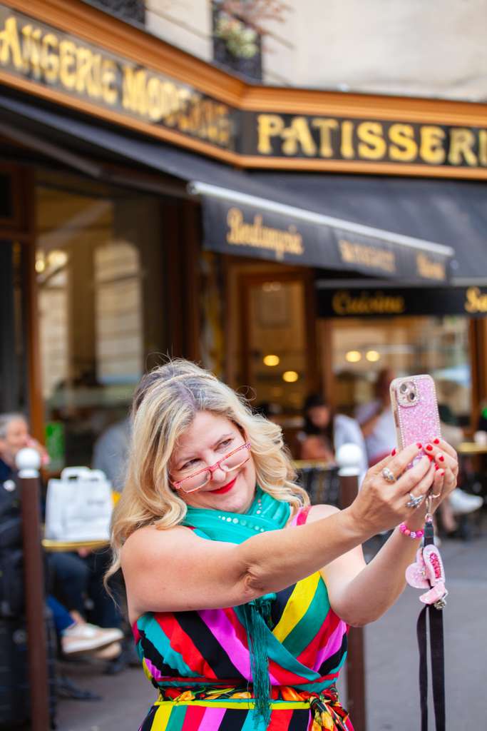 Sarah taking a selfie in a striped dress outside a Paris boulangerie patisserie