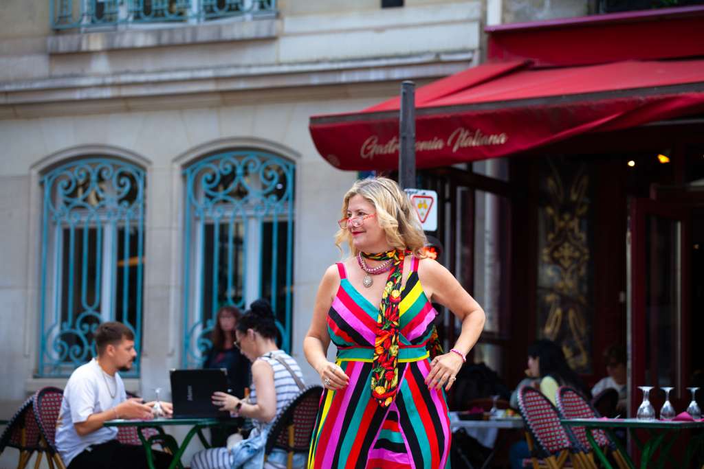 Sarah standing in a striped dress outside a Paris cafe